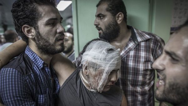 Un padre ayuda a su hijo herido en una escuela en Gaza atacada por Israel. (Foto: Efe)
