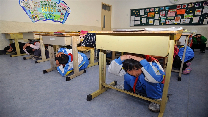 Escolares chinos cubren las cabezas durante un simulacro de terremoto con motivo del tercer aniversario del terremoto de Sichuan