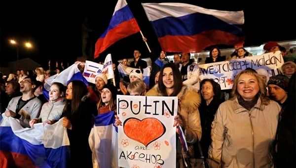 Una mujer sostiene un cartel en el que se lee "Putin" y se ve un corazón mientras participa en una concentración para festejar la adhesión de Rusia y Crimea. (Foto: efe)