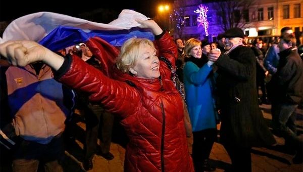 Unas personas sostienen banderas rusas mientras participan en una concentración para festejar la reunificación de Crimea con Rusia, en la plaza de Lénin en Simferópol, la capital de Crimea, Ucrania. (Foto: efe)