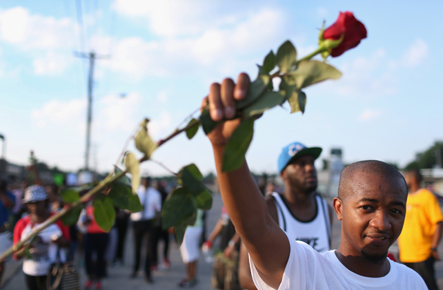 Un manifestante sostiene una rosa durante la marcha en Ferguson para pedir justicia por la muerte de Michael Brown. (Foto: publico.es)
