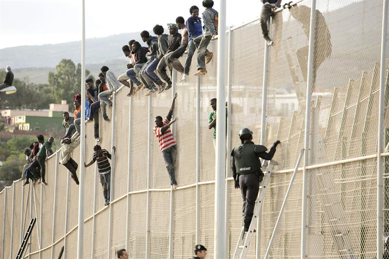 Un centenar de inmigrantes permanecen encaramados en la valla fronteriza entre Melilla y Marruecos. (Foto: EFE)