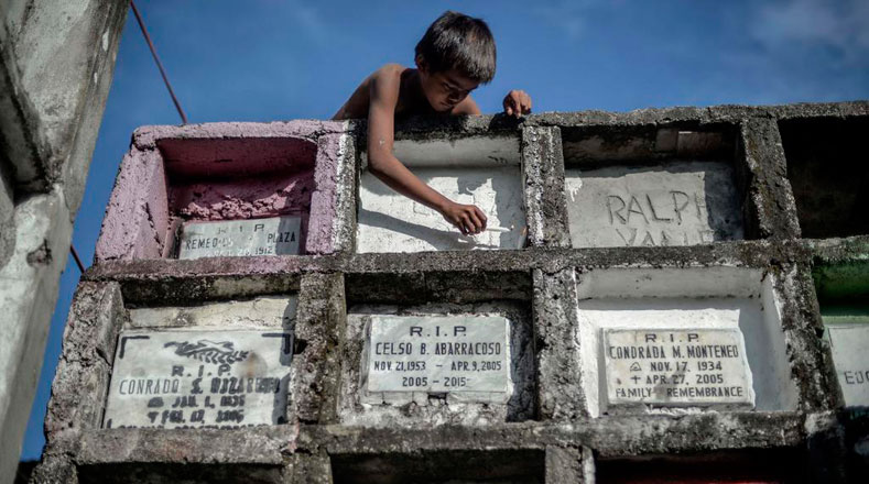 Niño local coloca vela en tumba durante el Día De Los Muertos en Navotas, Filipinas. (Foto: Xinhua)