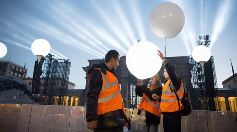 Trabajadores reemplazan la luz que alumbra los globos de helio, que serán soltados al finalizar los actos conmemorativos.