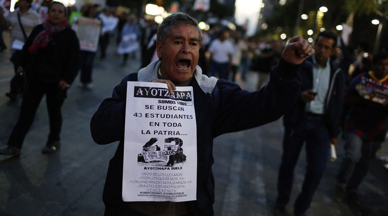 Este hombre grita mientras sostiene un cartel que reza “Ayotzinapa somos todos… Se buscan 43 estudiantes en toda la patria”.