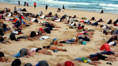 Un grupo de unos 400 manifestantes participan en una protesta y entierran sus cabezas en la arena en una playa de Sidney, Australia. (Fuente: Reuters)