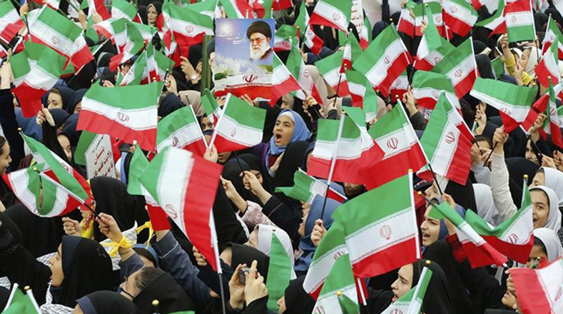 Estudiantes iraníes ondean la bandera de su país con alegría y entusiasmo.