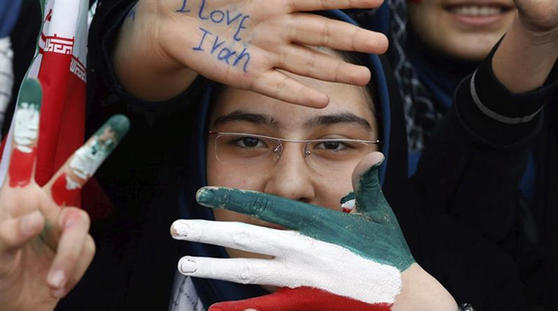 Una estudiante  muestra su mano pintada con los colores de la bandera de su país.