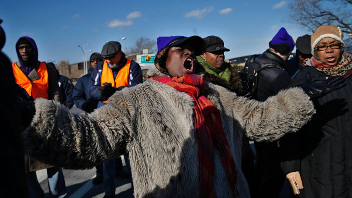 La manifestante Annette McCoy canta con otros miembros de un coro en un puente que conduce al Aeropuerto de La Guardia durante una marcha de protesta en Nueva York, 15 de enero de 2015