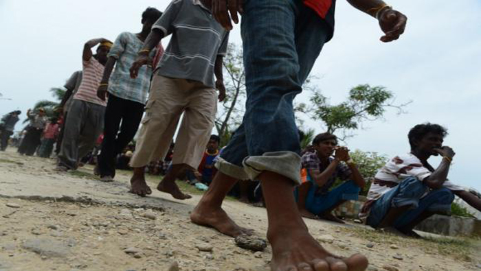 Migrantes de Bangladesh rescatados en el mar forman filas para cumplir con el proceso de identificación realizado por las autoridades de Indonesia en Kuala Langsa, en la región de Aceh. (Andes)