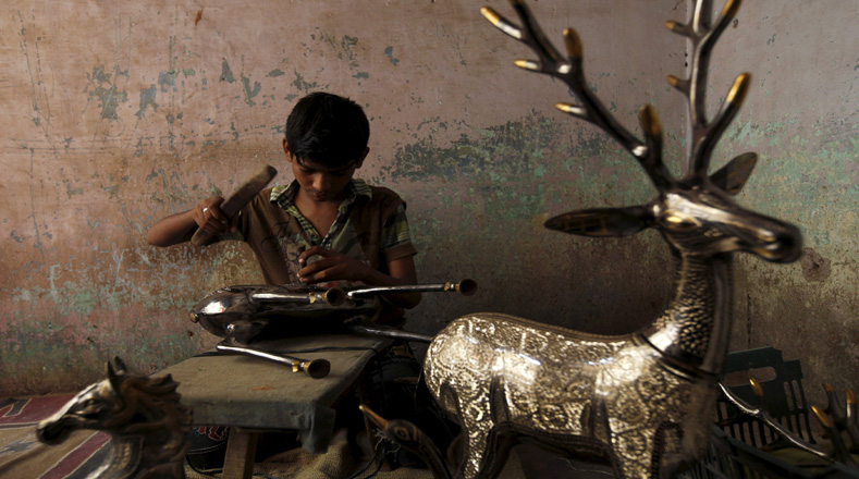Muzamil, un niño de 12 años , talla patrones en una escultura de bronce de los ciervos en un taller artesanal en Karachi, Pakistán. 