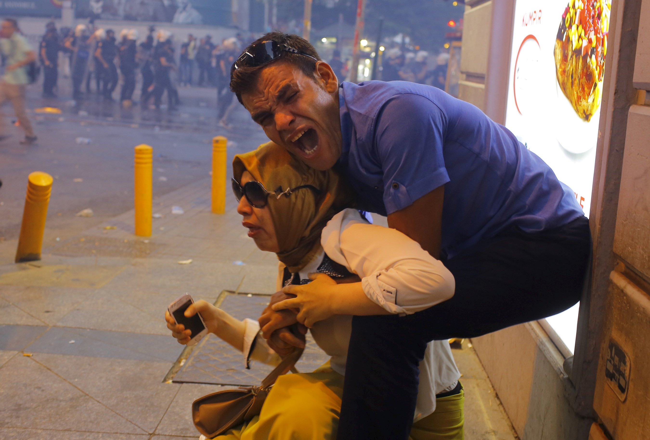 Una pareja, afectados por el gas lacrimógeno utilizado por la policía antidisturbios para dispersar a los manifestantes, reacciona en el centro de Estambul, Turquía 20 de julio de 2015