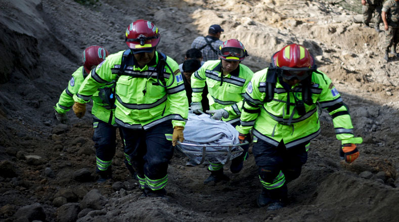 Los miembros del equipo de rescate llevan el cuerpo de una víctima, las fuertes lluvias barrieron un torrente de piedras y barro sobre decenas de viviendas.
