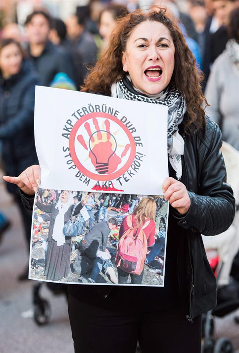 Una mujer sostiene un cartel escrito con "Detenga el terror" durante una manifestación kurda tras el ataque terrorista en una marcha por la paz en Ankara.