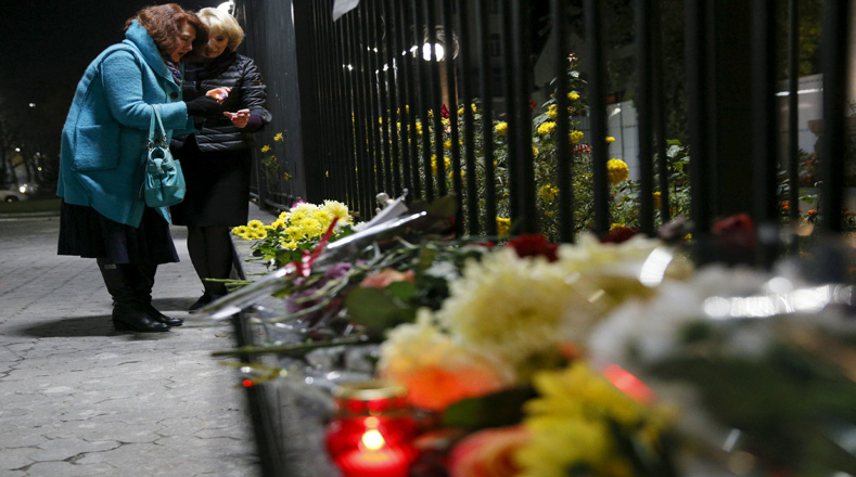 Mujeres encienden velas a las víctimas de un avión ruso que se estrelló en Egipto, en las afueras de la embajada rusa en Kiev, Ucrania.