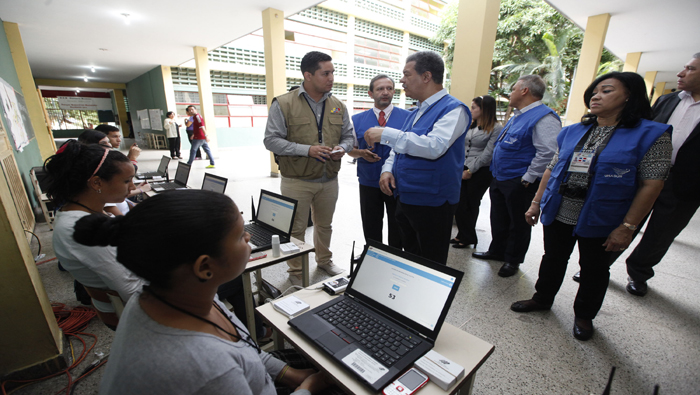 Integrantes de la misión electoral de la Unión de Naciones Suramericanas (Unasur) dirigida por el expresidente de República Dominicana Leonel Ferández (c), durante una visita a un centro de votación este domingo.