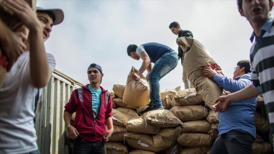 Hombres y mujeres sirios ayudan a repartir la asistencia humanitaria