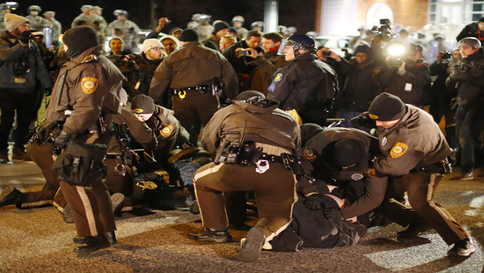 Varios policías detienen a manifestantes a las afueras de la Policía de Ferguson.