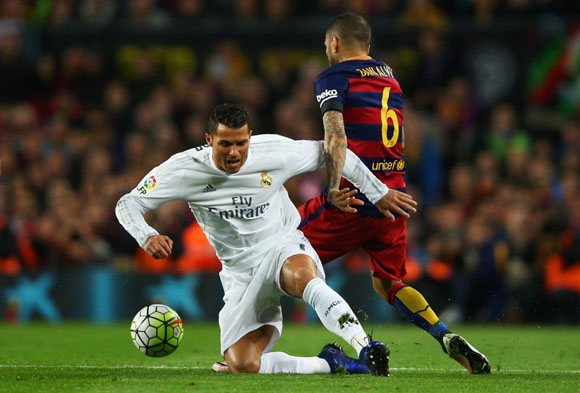 Cristiano Ronaldo del Real Madrid CF es derribado por Daniel Alves del FC Barcelona durante el partido en el Camp Nou.
