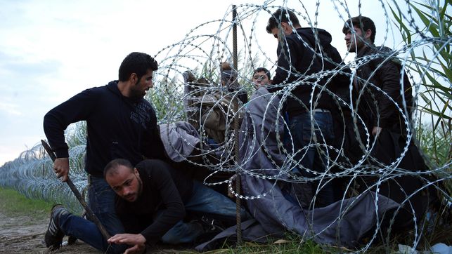 Refugiados entran en Hungría por debajo de la valla de la frontera húngara, cerca de Roszke.