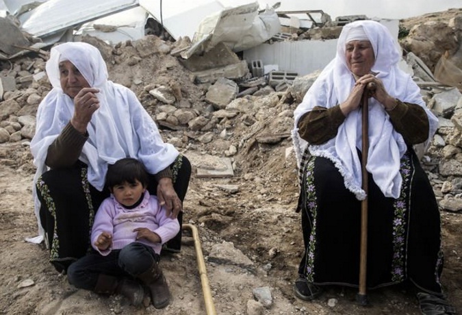 Mujeres palestinas se sientan en las ruinas de sus casas destruidas por ataques israelíes