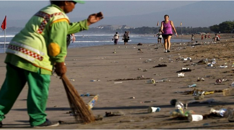 En la imagen se observa un trabajador del Gobierno de Indonesia limpiando los desechos mientras propios y extraños caminan sin importar lo que pasa alrededor.
