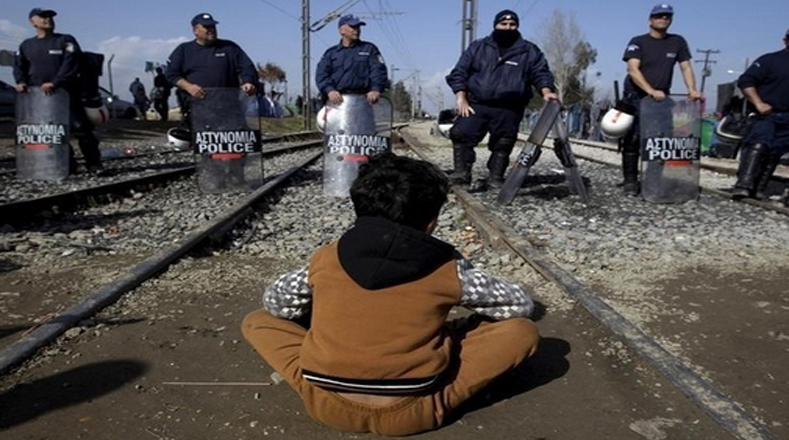 Este niño pide ante policías de Grecia que abran la frontera.