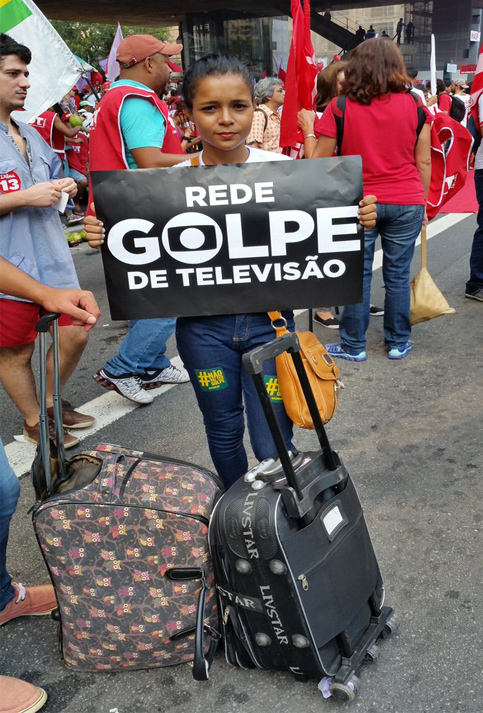 Una joven brasileña posa con un cartel en rechazo al golpe mediático en la nación brasileña.