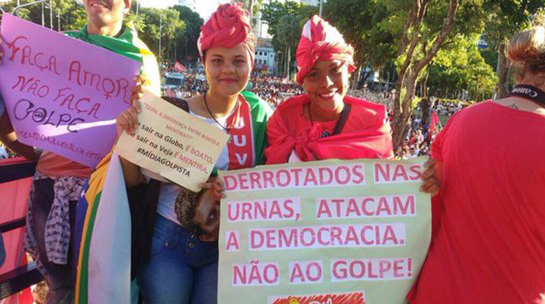 Mujeres jóvenes posan con un cartel que reza "Derrotados en las urnas, atacan la democracia".