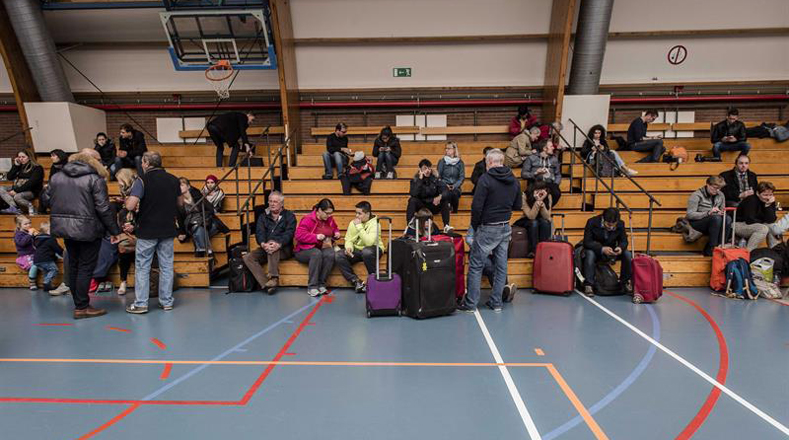Algunos pasajeros permanecen en un polideportivo en Zaventem, cerca de Bruselas. El sistema de transporte público también fue suspendido temporalmente. 