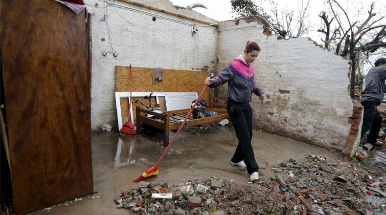 Una mujer limpia los escombros de una casa sin techo en Dolores. 