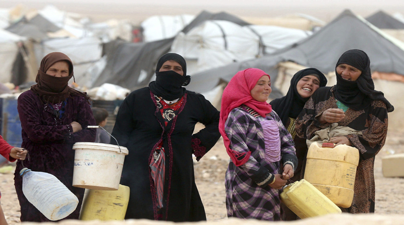 Aún en medio de la tragedia, refugiadas sirias esperan con alegría para llenar sus bidones de agua.