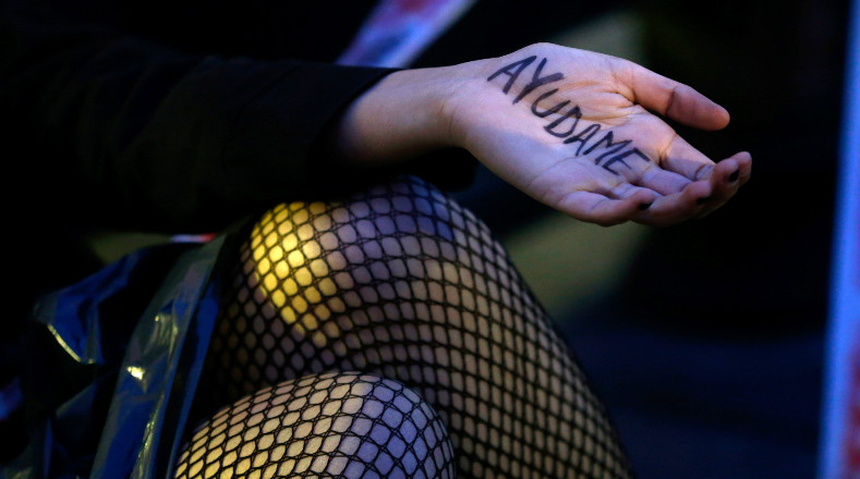 Una mujer muestra su mano con las palabras "Ayúdame" en reclamo de mayor protección.