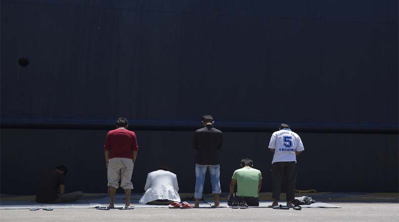 Inmigrantes afganos varados en Grecia rezan delante de un ferry atracado en el puerto de El Pireo, cerca de Atenas.