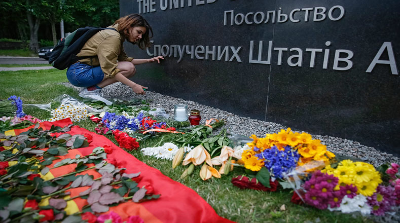 Una mujer enciende una vela en homenaje a las víctimas frente a la embajada estadounidense en Kiev (Ucrania).