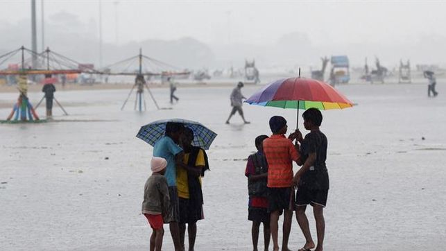 Varias personas caminan por la orilla parcialmente inundada en Marina Beach debido a un ciclón en Chennai, India.