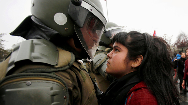 Una joven chilena mira retadoramente a un carabinero durante una manifestación en Santiago de Chile por el cuarto aniversario del golpe de Estado al presidente socialista Salvador Allende, este golpe daría paso a la dictadura de Augusto Pinochet.