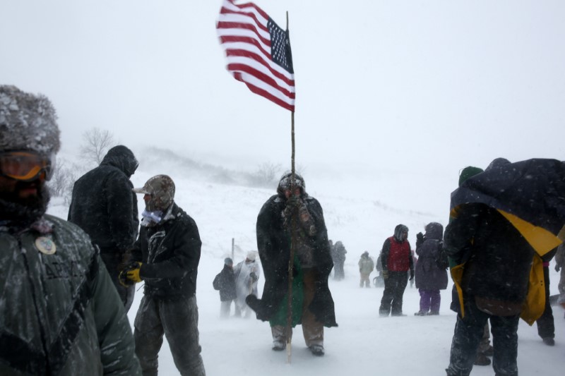 Un hombre sostiene una bandera de Estados Unidos mientras marcha con los protectores de agua contra los planes de construcción del oleoducto Dakota Access