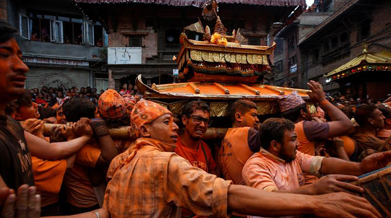 Los nepaleses trasladan un palanquín ceremonial mientras que otros se manchan polvo de color bermellón el uno al otro
