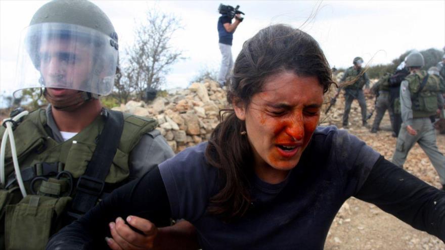 Un policía israelí detiene a una mujer palestina después de rociarle la cara con spray de pimienta en la ciudad de Hebrón, en la ocupada Cisjordania.