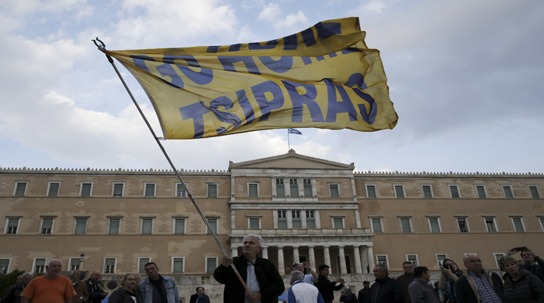 Afuera del edificio del Parlamento griego los manifestantes ondearon una bandera que dice "Go Home Tsipras".