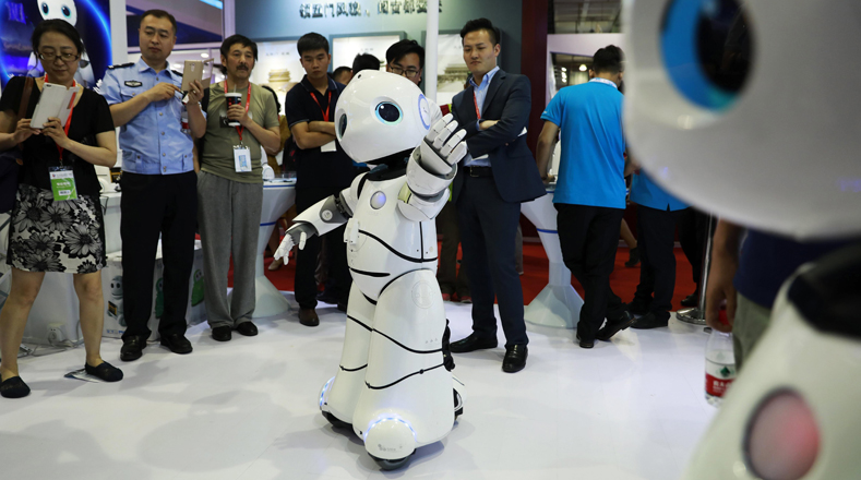 Varias personas observan las demostraciones de un robot en la Feria que se realiza en el Centro Internacional de Exposiciones de China. 