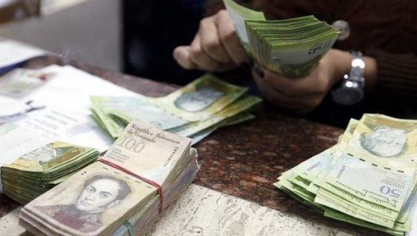 A cashier counts bolivars at money exchange in Caracas.