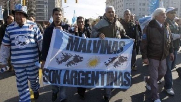 Argentines march with banner thats reads, "Malvinas belongs to Argentina."