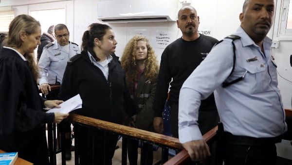 Palestinian teen Ahed Tamimi enters a military courtroom escorted by Israeli security personnel as her lawyer Gaby Lasky (L) stands near, at Ofer Prison, near the West Bank city of Ramallah, Feb. 13, 2018.