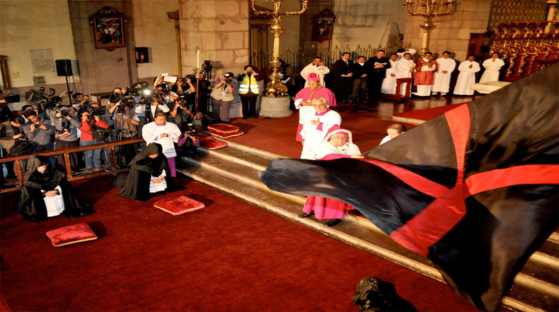 Al llegar al altar los clérigos se ponen de rodillas y después se acuestan representando la muerte de Jesús, en ese momento el Arzobispo ondula una bandera negra de gran tamaño que lleva en el centro una cruz de color roja.