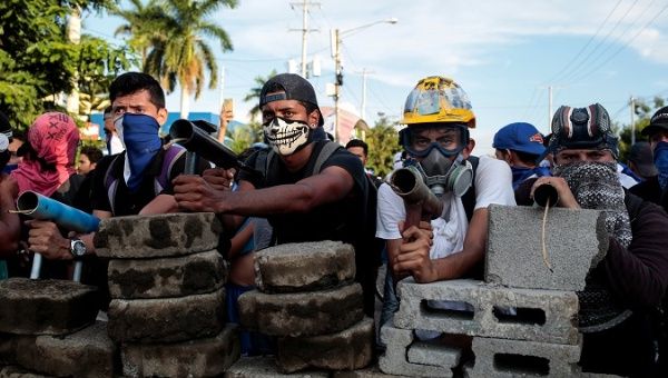 Demonstrators stand behind a barricade during clashes with riot police during a protest against Nicaragua