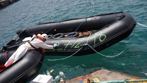 A rescuer pushes a migrant dinghy intercepted in the Strait of Gibraltar, July 11, 2018.