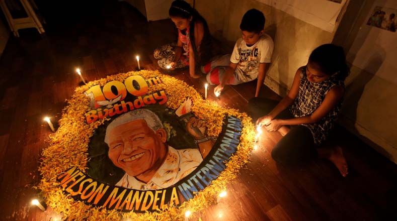 En la India, niños de la escuela de artes en Mumbai encendieron varios velas alrededor de una pintura para celebrar el día   internacional de "Madiba" en su cumpleaños.