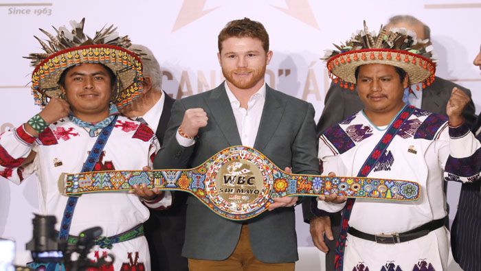 Canelo, campeón del Consejo Mundial de Boxeo (c), en Ciudad de México junto a indígenas huicholes que realizaron el decorado del cinturón.